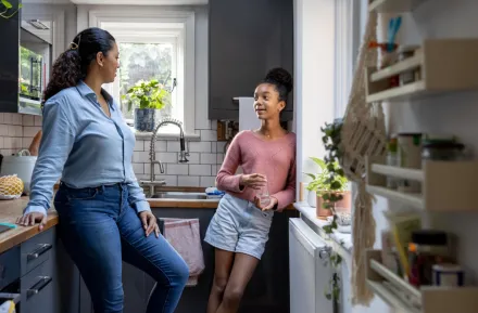 mom and teen daughter talking in the kitchen