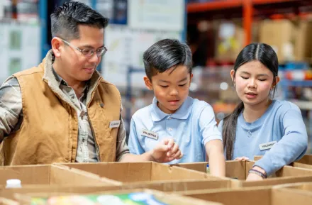 family volunteering and putting food into boxes at a food distribution center