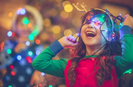 little girl laughing and playing with holiday lights