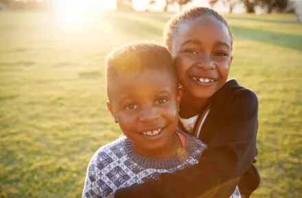 Black History Month events with smiling African American boy and girl hugging each other. 