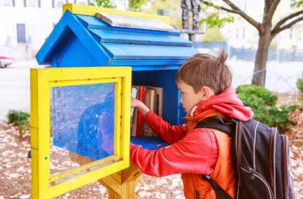 little boy looking at free books on the street