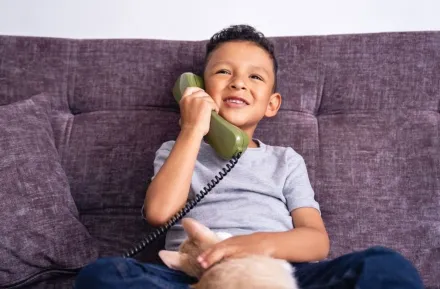 happy little boy talking on vintage green landline phone at home