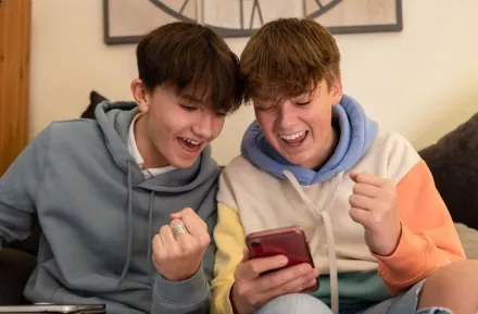 Two teenage boys playing and gambling on smart phones