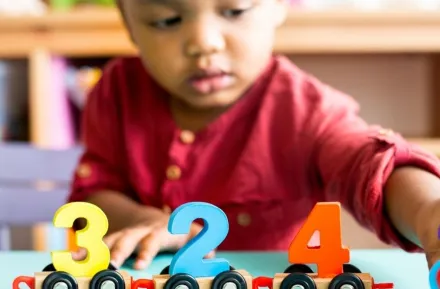Little boy playing with mathematics wooden toy at child care