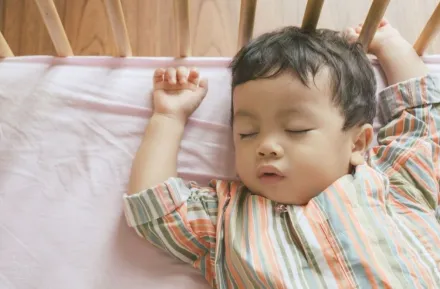 Little boy toddler adorably sleeping in his baby cot