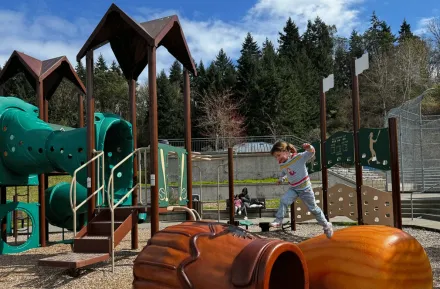 girl jumping across climbers at Shoreview Park's baseball playground