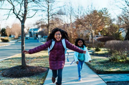 two girls running down the street happy to be out of school