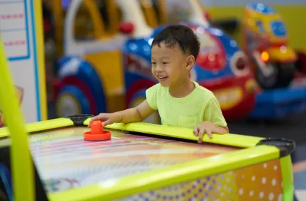 little boy playing air hockey at an arcade