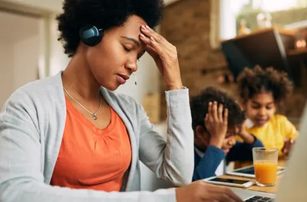 overcommitted mom looking stressed out with kids in the background