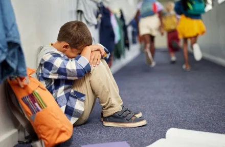 little boy sitting in corridor anxious at end of school 