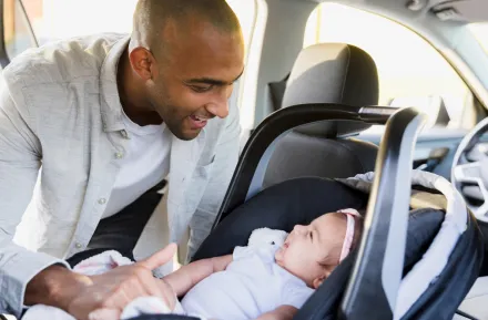 dad and girl in a car seat smiling at each other