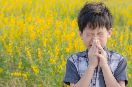 little boy in a field of yellow flowers with spring allergies