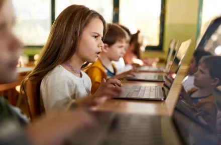 young girl studying on laptop in classroom