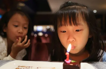 little girl blowing a birthday candle