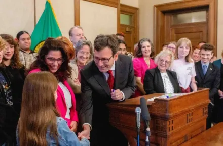 Gov. Bob Ferguson handing over his pen to a child