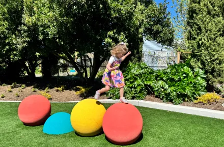 young girl hopping across bright play structure at a new playground opening this weekend in Seattle