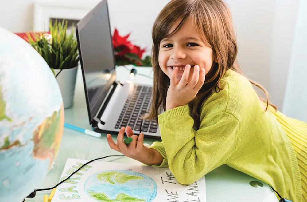 Young girl with a globe and computer making a Save The Earth sign