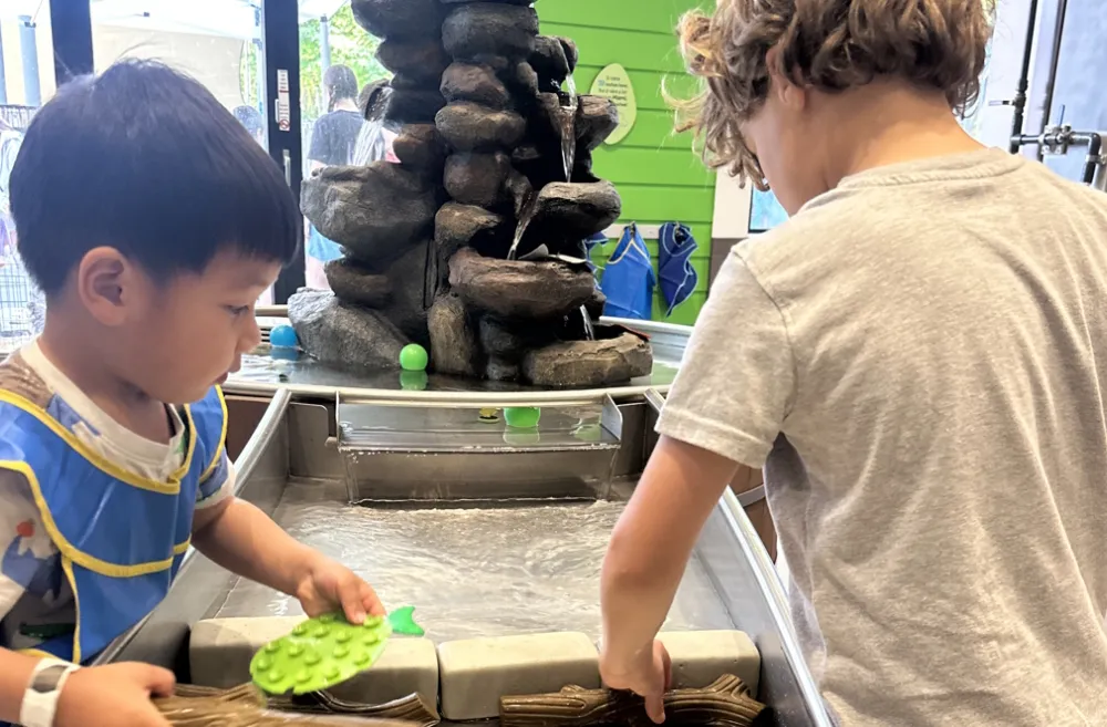 two kids working together at a water exhibit at KidsQuest Children's Museum