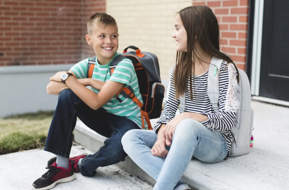 kids sitting on steps outside smiling at each other