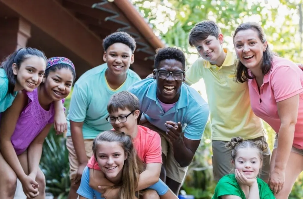 Group of teens and camp staff smiling together outdoors at camp
