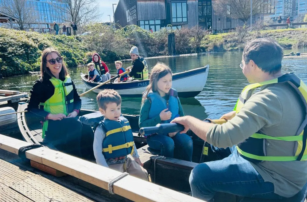 family of four rowing in a rowboat on South Lake Union in Seattle at The Center for Wooden Boats