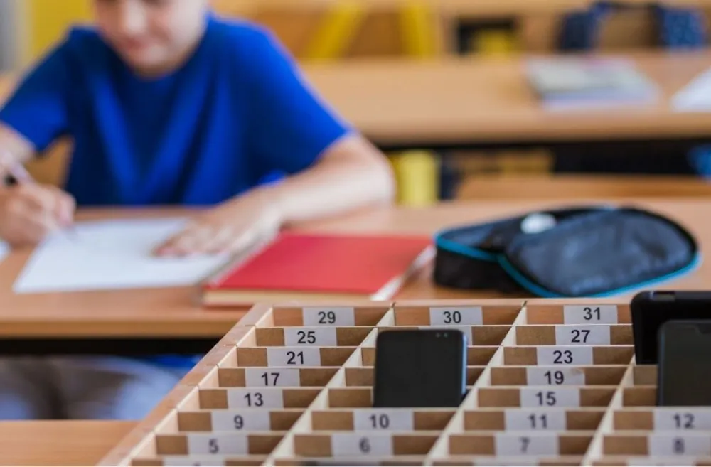 School kids placing putting phones away during class