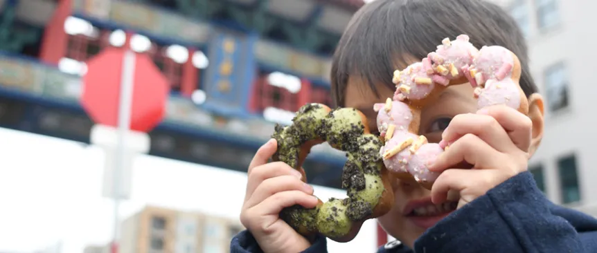 kid holding dochi mochi doughnuts up to his face best eats with kids in seattle's chinatown international district