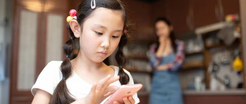 girl using cell phone while mom looks on worried
