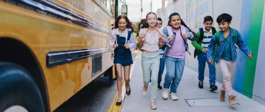 Kids walking next to a school bus on their way back to school