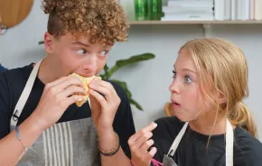 Siblings taste the Greek chicken pita sandwiches they made with Chef Joel