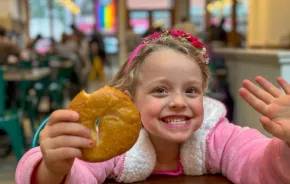 Young girl smiling and holding a bagel at one of seattle's best bagels shops