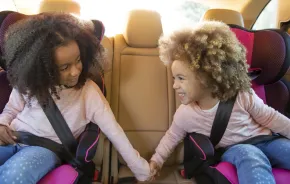 Sisters in the backseat of a car playing a car game on a family road trip