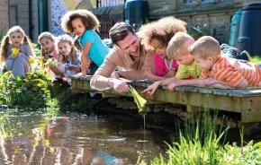 A group of kids on a small bridge over a pound at a seattle outdoor summer camp