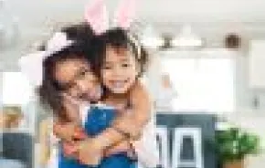 Cute sisters wearing bunny ears share a hug. Best Seattle Easter egg hunts for kids and families 2024