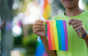 a child holds a rainbow Pride flag