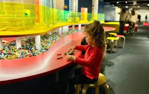 Young girl playing with loose Lego bricks at the new MOHAI Towers of Tomorrow exhibit