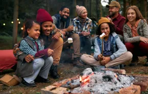 Families around a campfire roasting marshmallows and playing a campfire game