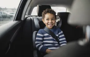 boy smiles in the backseat of a car