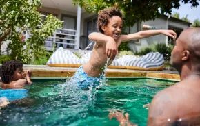 Boy jumping in his father in a swimming pool and demonstrating water safety for families 