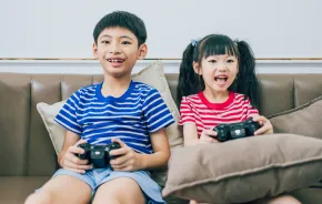 Boy and girl on the couch playing video games how to raise a healthy gamer