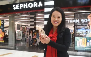 woman holding up a free gift from Sephora on her birthday