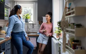 mom and teen daughter talking in the kitchen