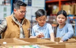 family volunteering and putting food into boxes at a food distribution center