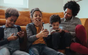 mom and three kids playing cell phone game