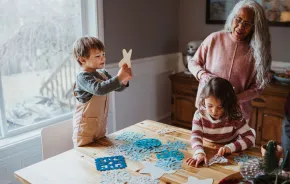 A family crafts snowflakes together in front of a window as a winter activity
