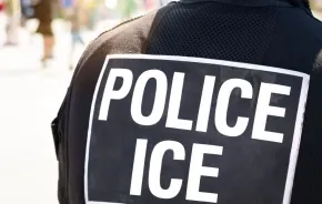 POLICE ICE marking on the back of a hi-visibility stab proof vest worn by a police officer