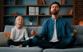 young father teaching little daughter meditation