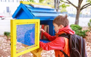 little boy looking at free books on the street