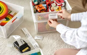 woman holding mobile label printer sticker with kids toys