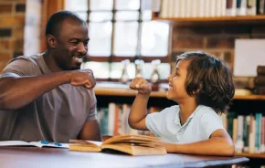Teacher and student giving each other a high five in a library